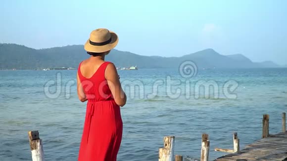 两个视频镜头穿着红色长裙的女人这位穿红色衣服的年轻女子在码头上花钱远远地看着视频的预览图