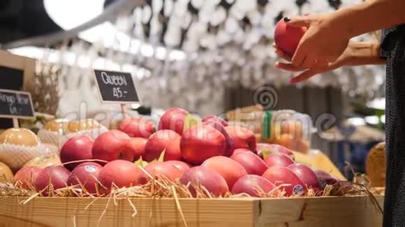年轻的混血女人在杂货店超市挑选有机红苹果水果4K视频的预览图