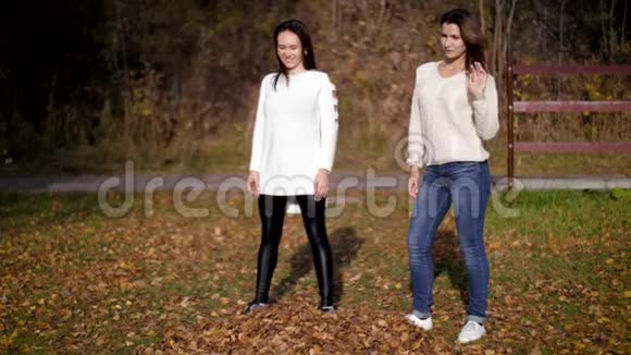 两个美丽的女人在秋天的花园里扔金叶女孩跳玩得开心像孩子一样4k60fps慢动作视频的预览图