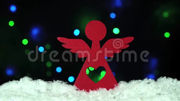 圣诞节装饰红色木制天使在雪地上闪耀的背景灯光视频的预览图