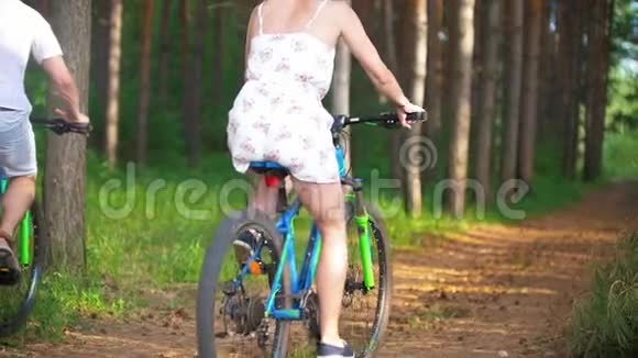年轻夫妇在夏天的森林里骑自行车穿过云杉树枝视频的预览图