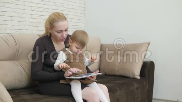 妈妈和小女儿坐在沙发上拿着平板电脑视频的预览图