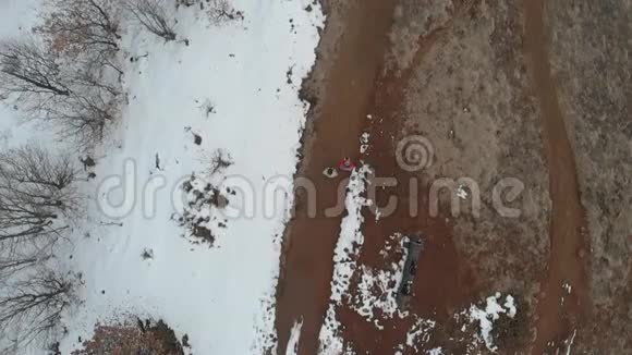 空中一对夫妇在乡间小路上散步路上有雪和树视野正上方动作缓慢视频的预览图
