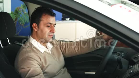 一个细心的人正在研究汽车的方向盘和沙龙里的按钮视频的预览图