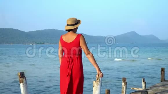 两个视频镜头这位穿红色衣服的年轻女子在码头上花钱远远地看着戴帽子的女人看着视频的预览图