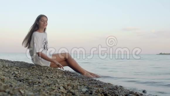 一个体贴的女人坐在沙滩上摸石头视频的预览图