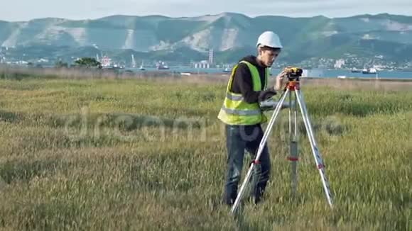 一名穿工作服的男性测量员调整施工现场的设备景观设计大地测量的概念视频的预览图