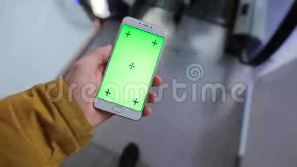 商场自动扶梯中使用绿色屏幕智能手机的男性手视频的预览图