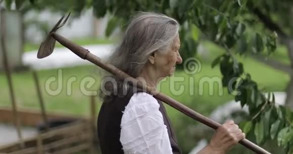 一位扛着锄头的老妇人的肖像视频的预览图