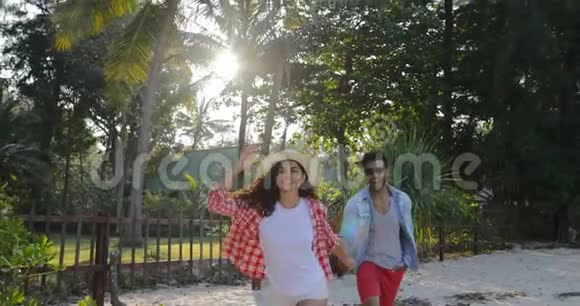 在热带棕榈树公园的交流中女孩牵着男人的手情侣奔跑着说着快乐的微笑视频的预览图