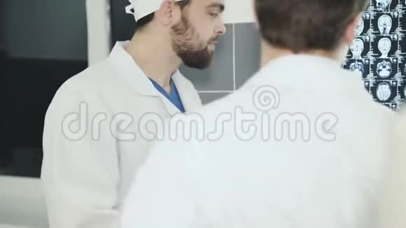 后景两位医生在医院的核磁共振显示中提供建议4K视频的预览图
