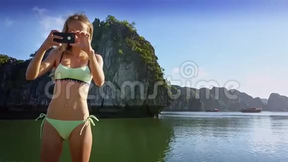 年轻女子在船上用Iphone和帆拍照视频的预览图