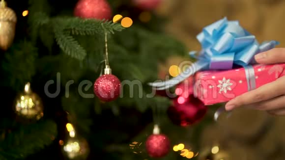 用红色的包装纸用蓝色的大丝带把圣诞礼物递给女性女人的手视频的预览图