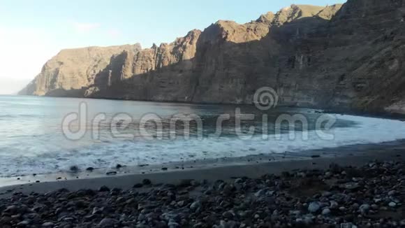 洛斯吉甘特斯悬崖从海滩上俯瞰大海早上在特内里费岛大西洋海浪和火山海滩视频的预览图