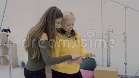 两个女人在工作室里讨论拍的照片看手机屏幕视频的预览图