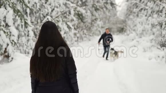 在冬天的森林里女孩张开双手背着她站着一个带着一只哈士奇狗的男人跑过来迎接她A视频的预览图