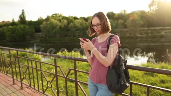 女人用智能手机站在桥上的户外嬉皮士女孩用电话上网发短信和视频的预览图