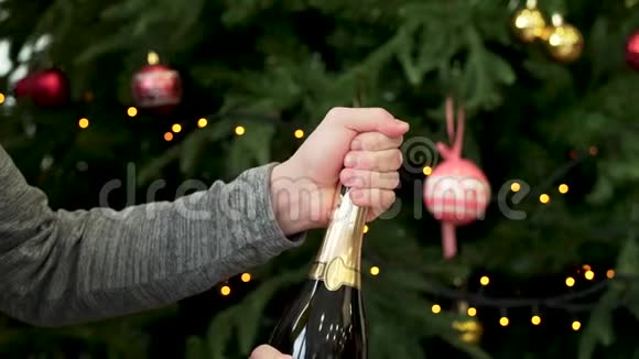 男人双手打开一瓶香槟装饰圣诞树背景新年庆祝理念男子手视频的预览图