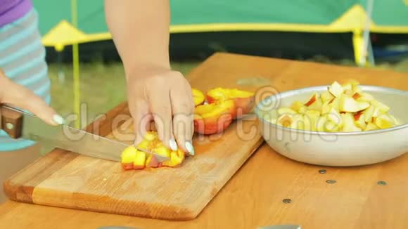 女人的手把苹果放在一个碗里放着水果沙拉野餐视频的预览图