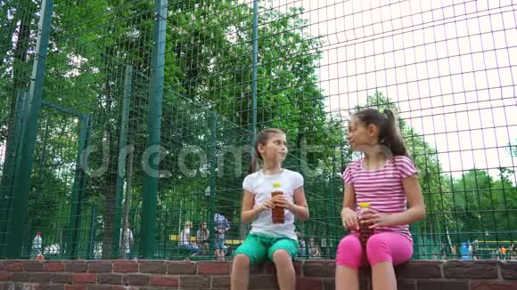 两个白种人的孩子在公园户外讲秘密笑着喝酒视频的预览图