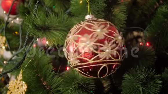 特写4k镜头红色的闪闪发光金色的闪光在圣诞树树枝上旋转视频的预览图