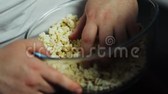 胖子手里拿着玻璃碗里的爆米花看电视节目吃东西视频的预览图