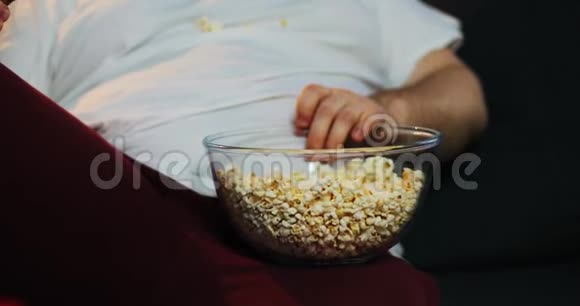胖子用手从碗里取出爆米花视频的预览图