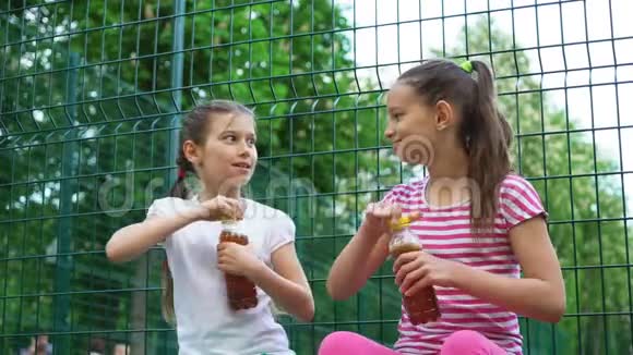 两个白种人的孩子在公园户外讲秘密笑着喝酒视频的预览图
