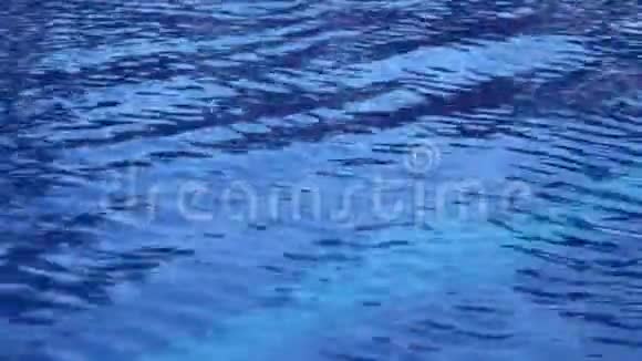 游泳池里的纯蓝色水的波浪表面有光反射漂亮的背景视频的预览图
