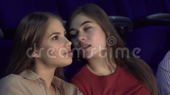 两个快乐的女朋友在看电影时窃窃私语视频的预览图