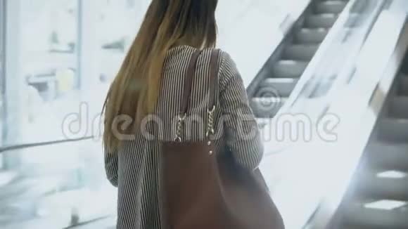 年轻漂亮的女人要在现代化的办公楼工作女商人上了电梯用上了智能手机视频的预览图