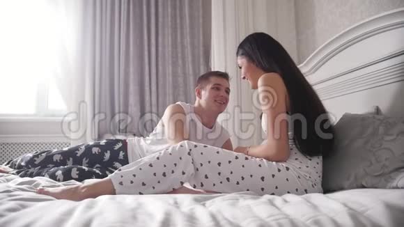 快乐的情侣躺在床上笑着拥抱着视频的预览图