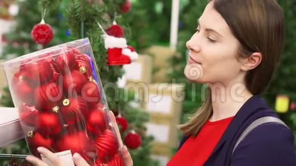 买圣诞装饰品的女人女性选择圣诞球背景圣诞树视频的预览图