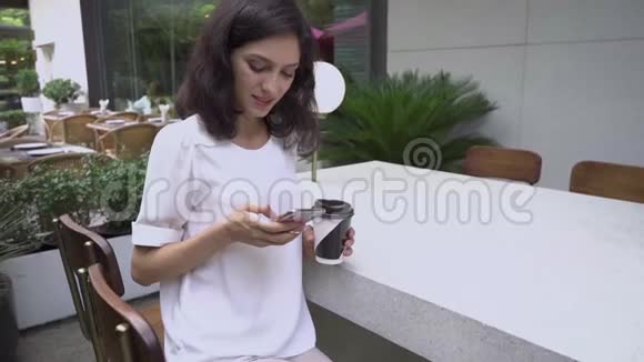 超级慢动作年轻的商务小姐在城市咖啡馆有智能手机视频的预览图