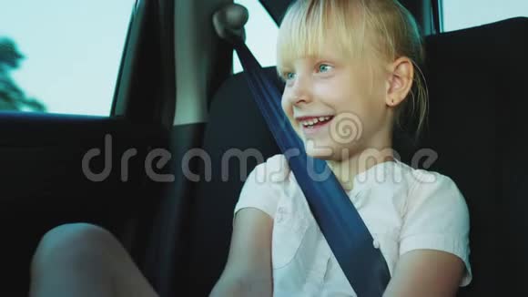 一个6岁的金发女孩喜欢在车里旅行坐在后座系好安全带视频的预览图