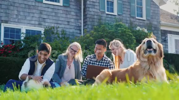 一群朋友一起休息坐在草坪上旁边有一只小狗和一只狗使用笔记本电脑视频的预览图