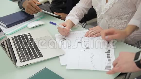 年轻员工正在现代办公室用笔记本电脑在桌子上检查文件视频的预览图