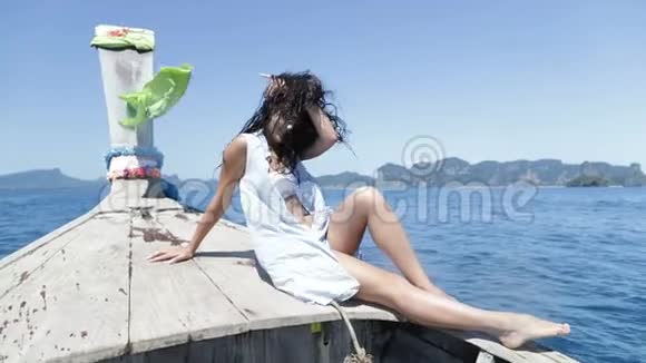 美丽的布鲁内特女士坐在泰国的小船上快乐地微笑着年轻的女孩在海洋景观上视频的预览图