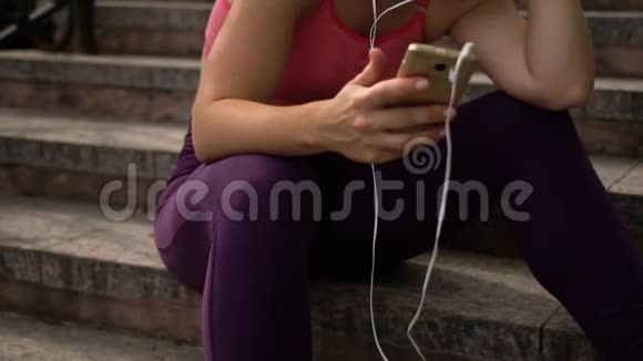 戴耳机的年轻女运动员选择音乐视频的预览图