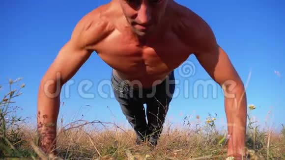 年轻的运动男子与裸露的躯干进行俯卧撑与拍自然慢动作视频的预览图