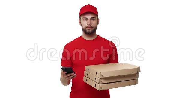 送货男孩穿着红色制服拿着一叠比萨饼盒在手机上检查订单孤立于白色之上视频的预览图