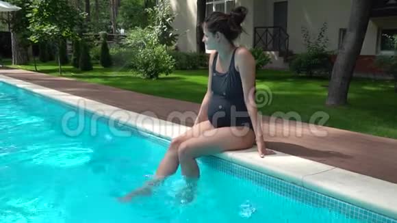 一个漂亮的怀孕女孩穿着一件泳衣坐在游泳池附近视频的预览图