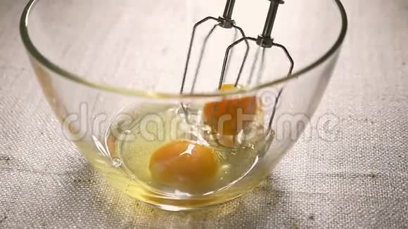 电动搅拌器将鸡蛋打在玻璃碗里烹饪特写慢动作视频的预览图