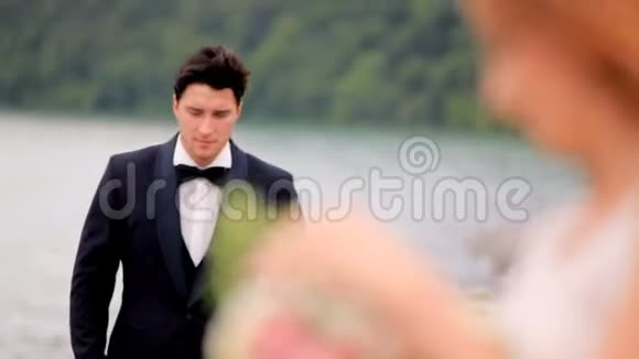 新婚快乐的新郎新娘在大江岸的大山背景下结婚格鲁吉亚视频的预览图