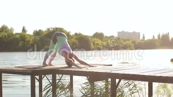 灵活的年轻女孩在一个小湖附近做瑜伽视频的预览图