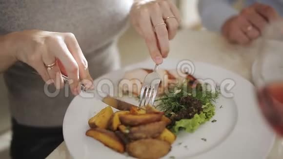 在餐馆里用刀叉吃饭的女孩在餐馆吃午饭的女人视频的预览图