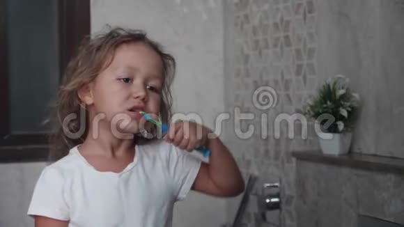 小女孩正在浴室里用牙刷刷牙视频的预览图