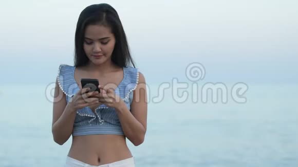 年轻快乐的亚洲旅游妇女在海滩边打电话视频的预览图