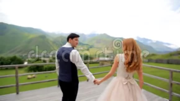 新婚快乐的新婚夫妇在他们的婚礼上在群山的背景下结婚照会格鲁吉亚视频的预览图