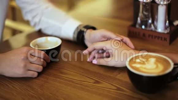 年轻一对情侣正坐在咖啡馆里喝着咖啡开心地笑着双手合拢视频的预览图